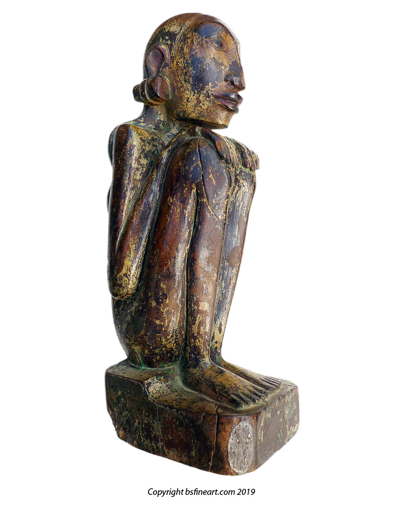 Bali female anamist figure of slender form and seated in a typical hunkerred position